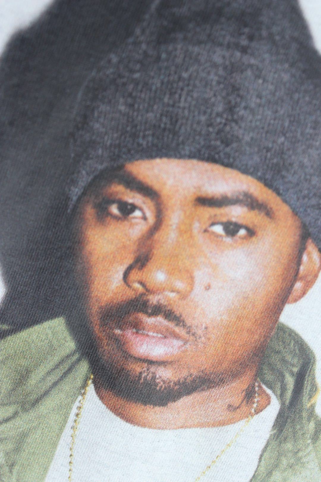 Graphic T-shirt close-up: face portrait in dark beanie with Nasty Nas text