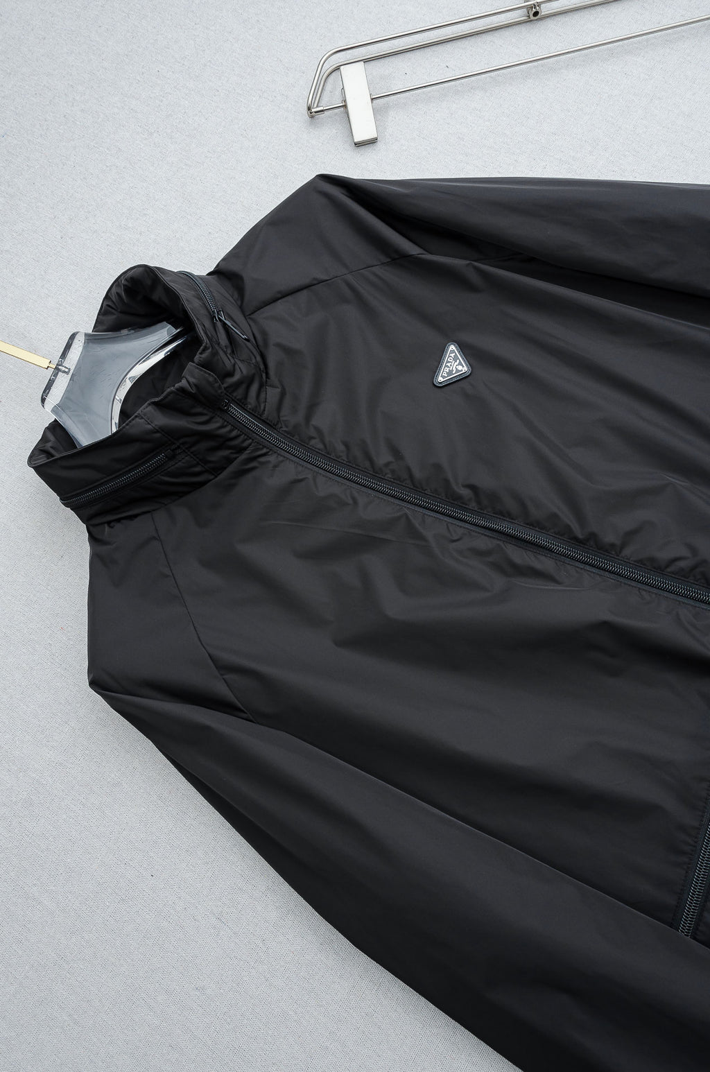 Prada long jacket front panel with diagonal logo patch and dark fabric texture