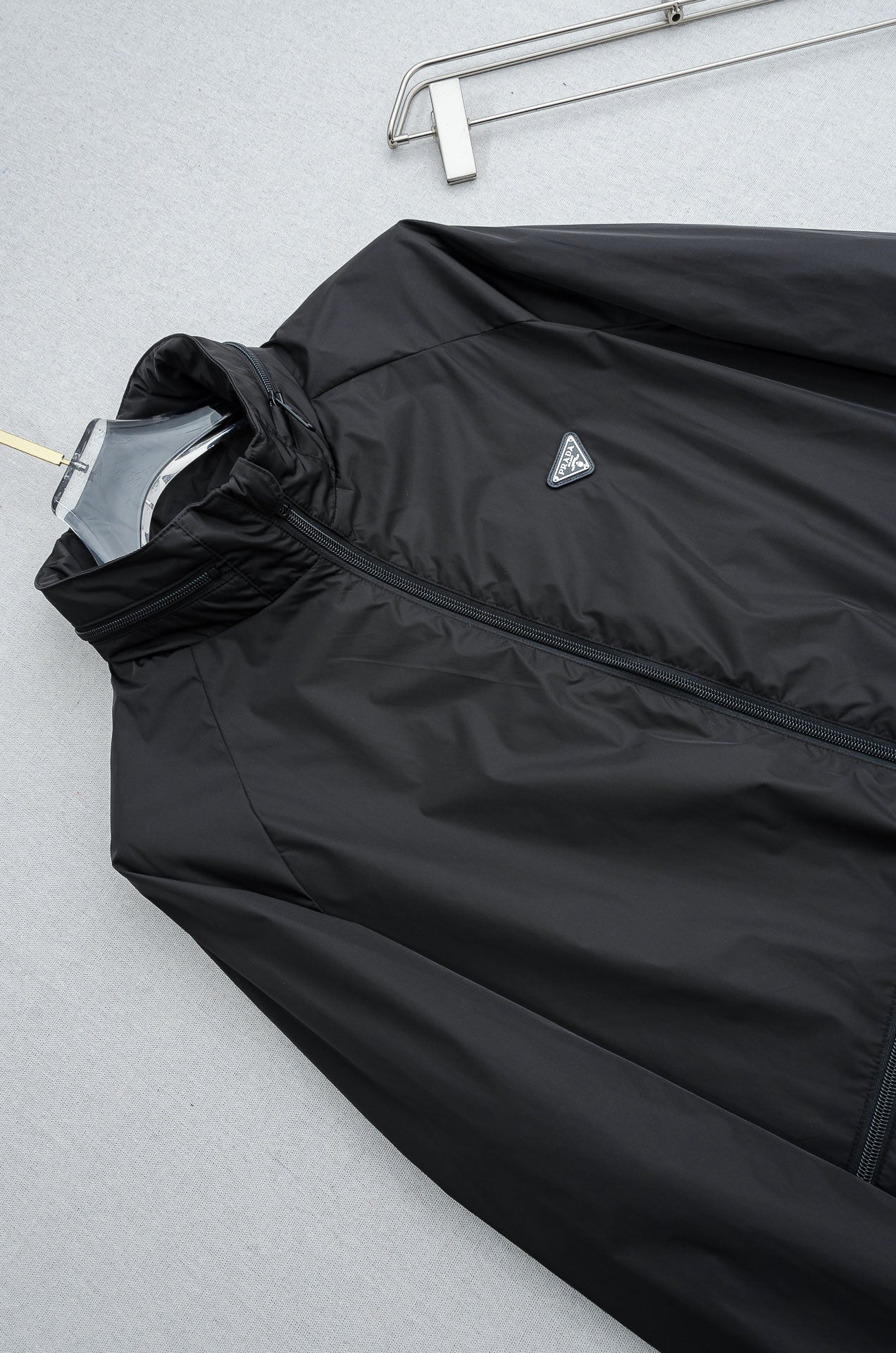 Prada long jacket front panel with diagonal logo patch and dark fabric texture