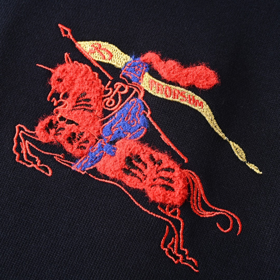 Close-up of red, blue, and yellow embroidered polo player graphic on dark navy sweatshirt