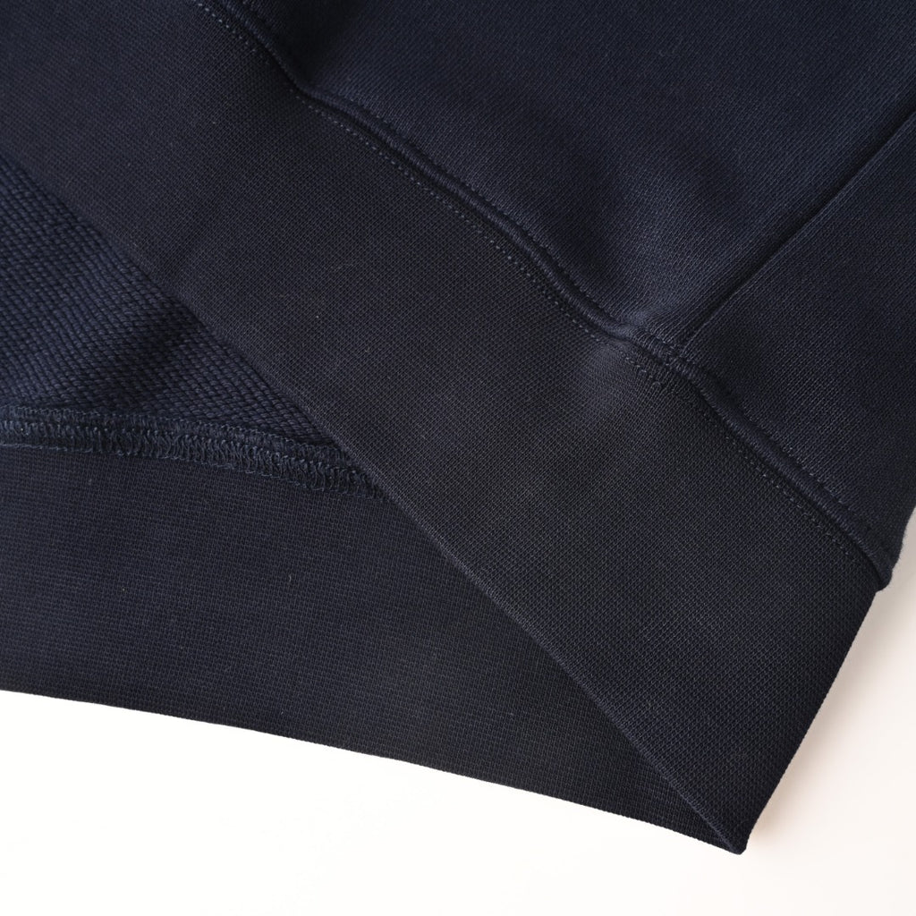 Dark navy sweatshirt hem and sleeve seam detail, long-sleeve cuff visible