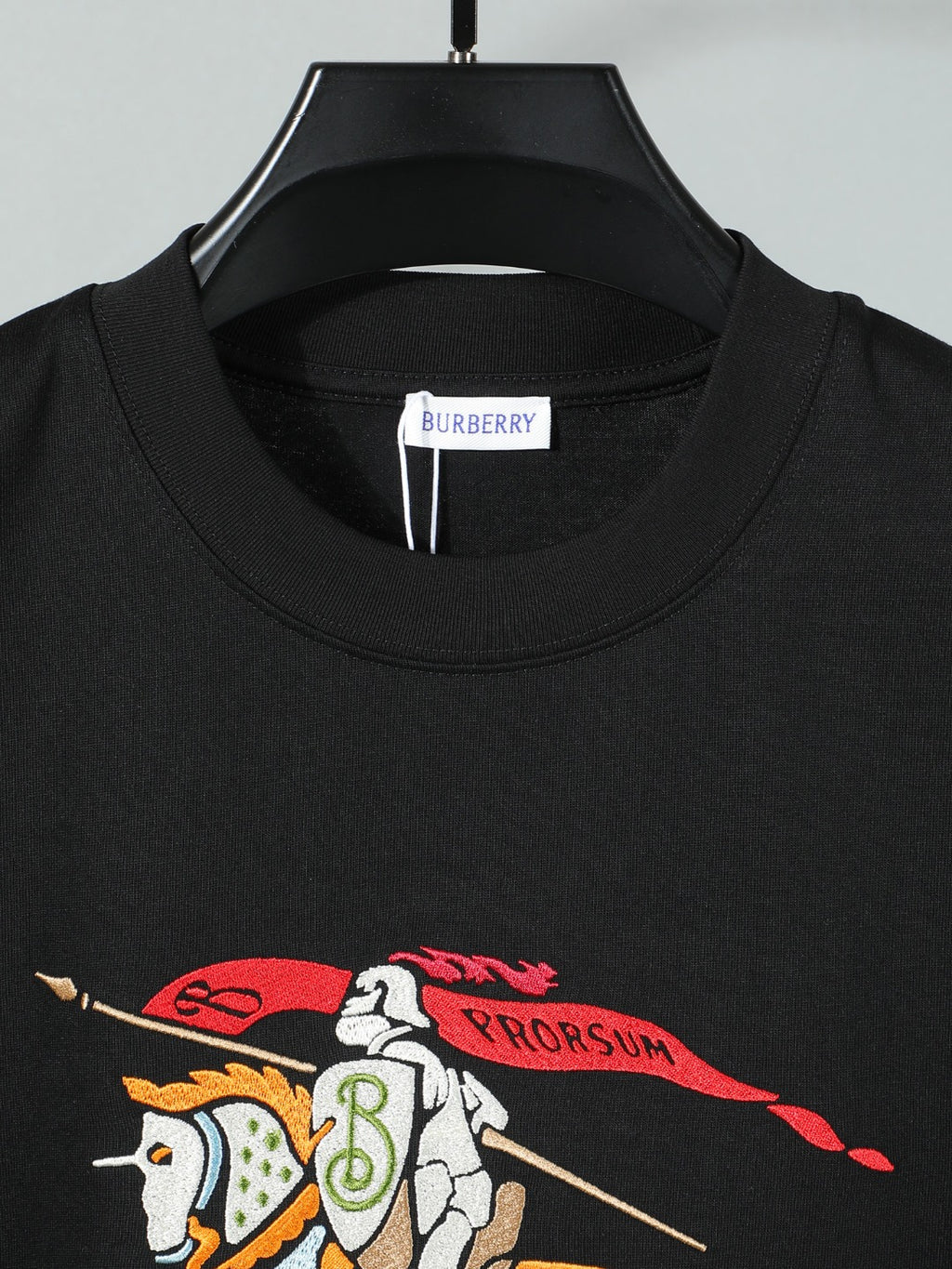Black crewneck T-shirt front with horse-and-rider graphic detail.