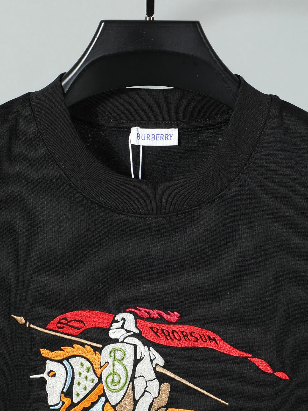 Black crewneck T-shirt front with horse-and-rider graphic detail.