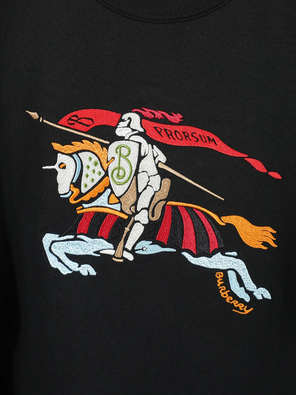 Black T-shirt front with horse-and-rider graphic, red ribbon and gold text accents.