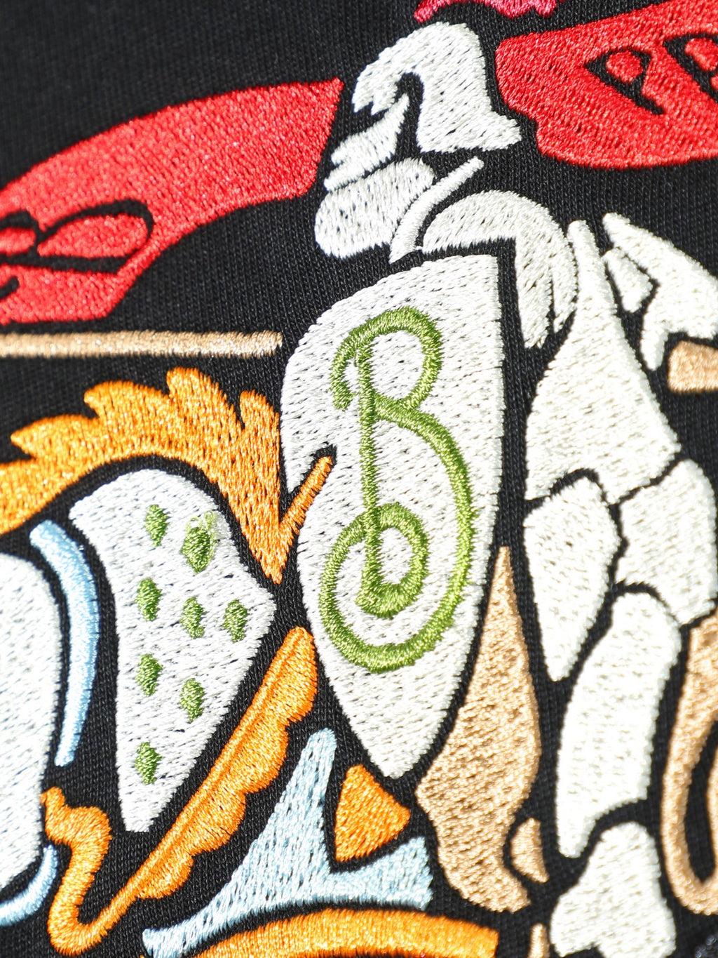 Close-up of embroidered-style horse-and-rider graphic on black T-shirt.