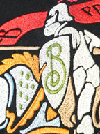Close-up of embroidered-style horse-and-rider graphic on black T-shirt.
