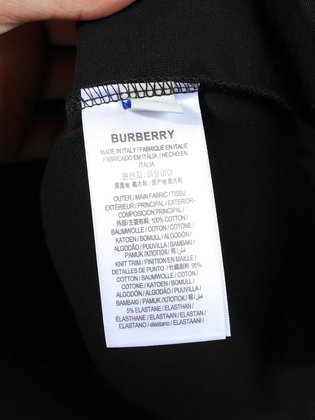 Black T-shirt inner care label with size and fabric composition text.