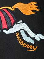Close-up of orange horse and 'Burberry' text on black T-shirt.