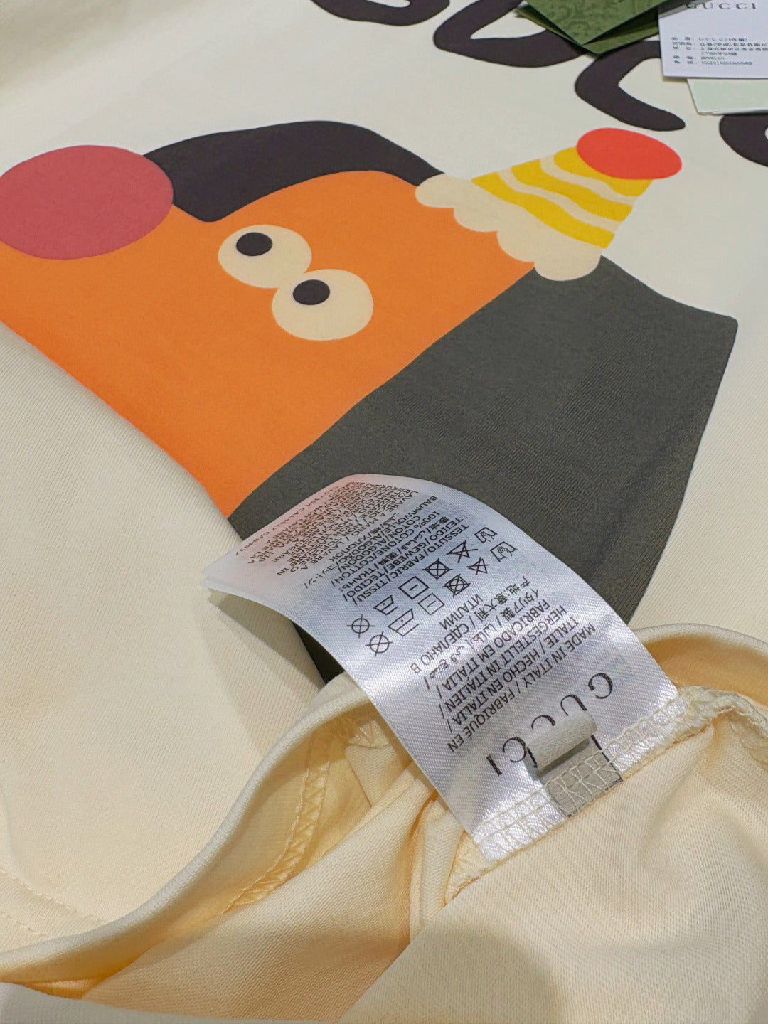 Detail view of cream T-shirt with orange and gray cartoon graphic