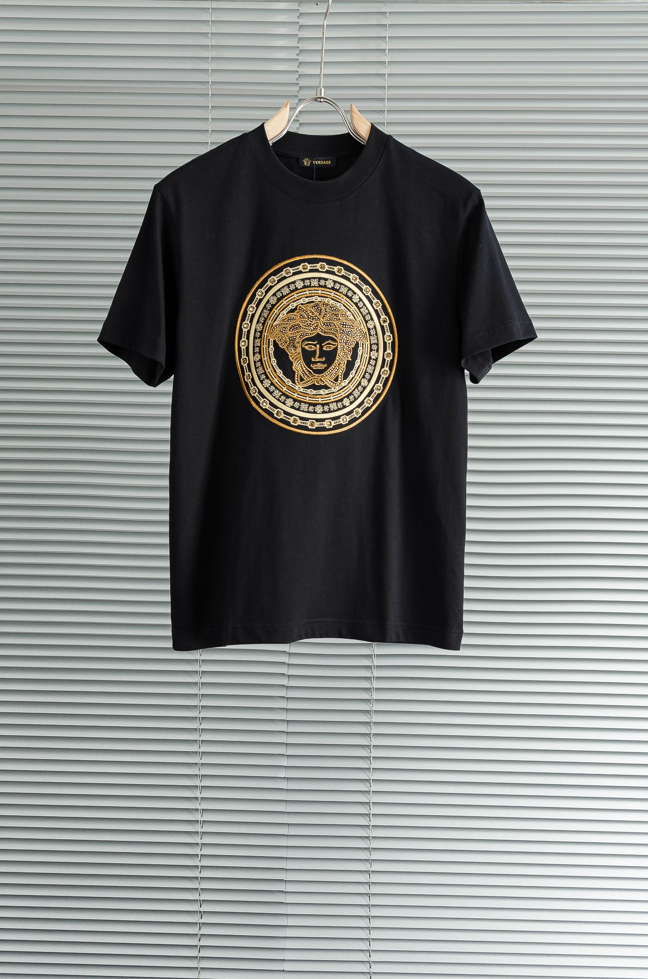 Black T-shirt with gold Versace-style medallion graphic on the chest