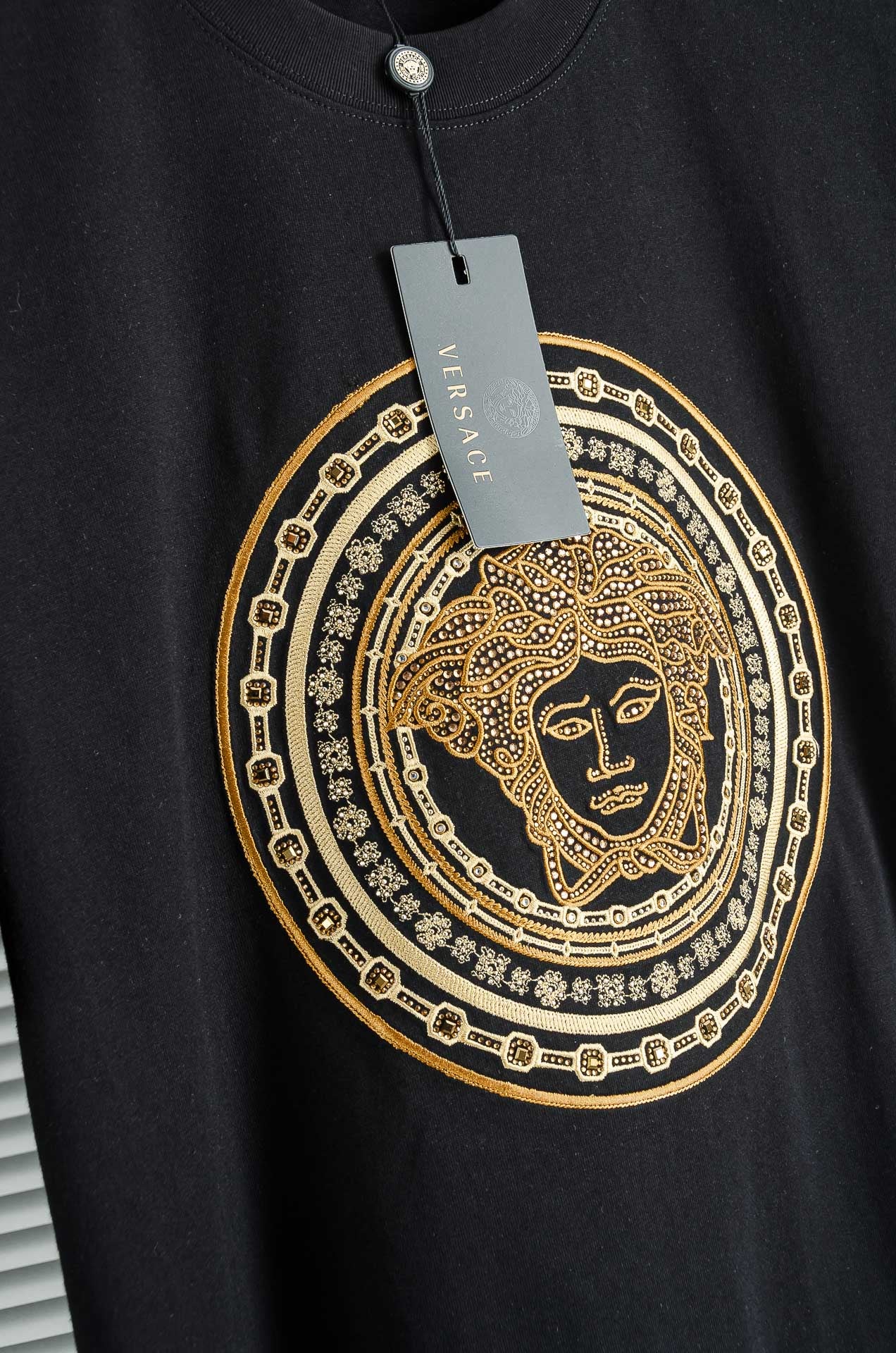Black T-shirt with gold Medusa-style medallion graphic