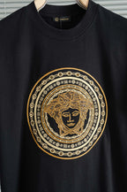 Black T-shirt close-up of gold Medusa-style emblem