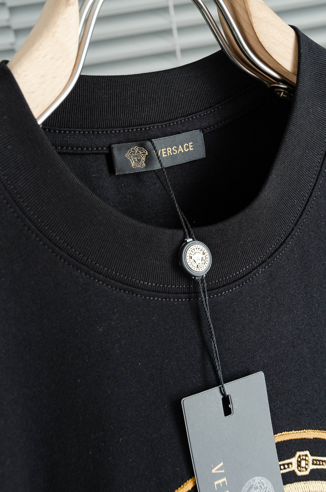 Black T-shirt neckline with Versace logo label and cord tag