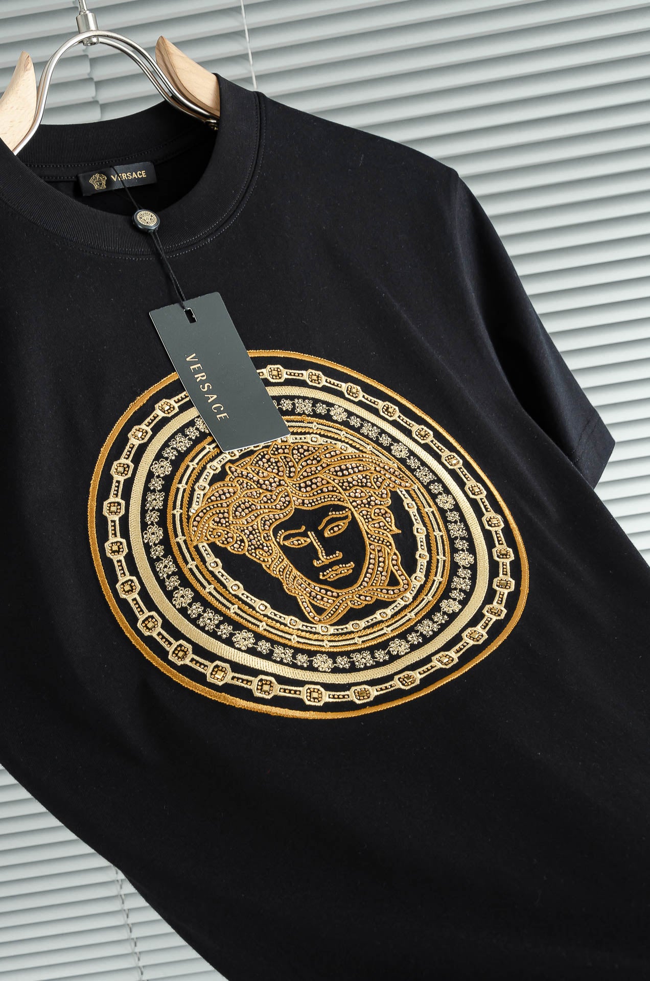 Black T-shirt with gold ornate circular Medusa-style graphic on the front
