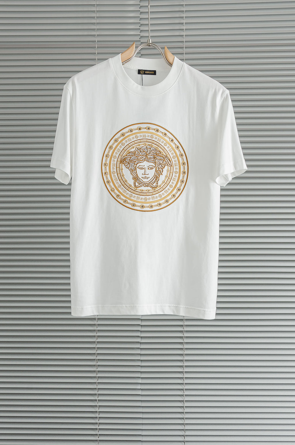 Versace white T-shirt with gold Medusa-style circular graphic on the chest
