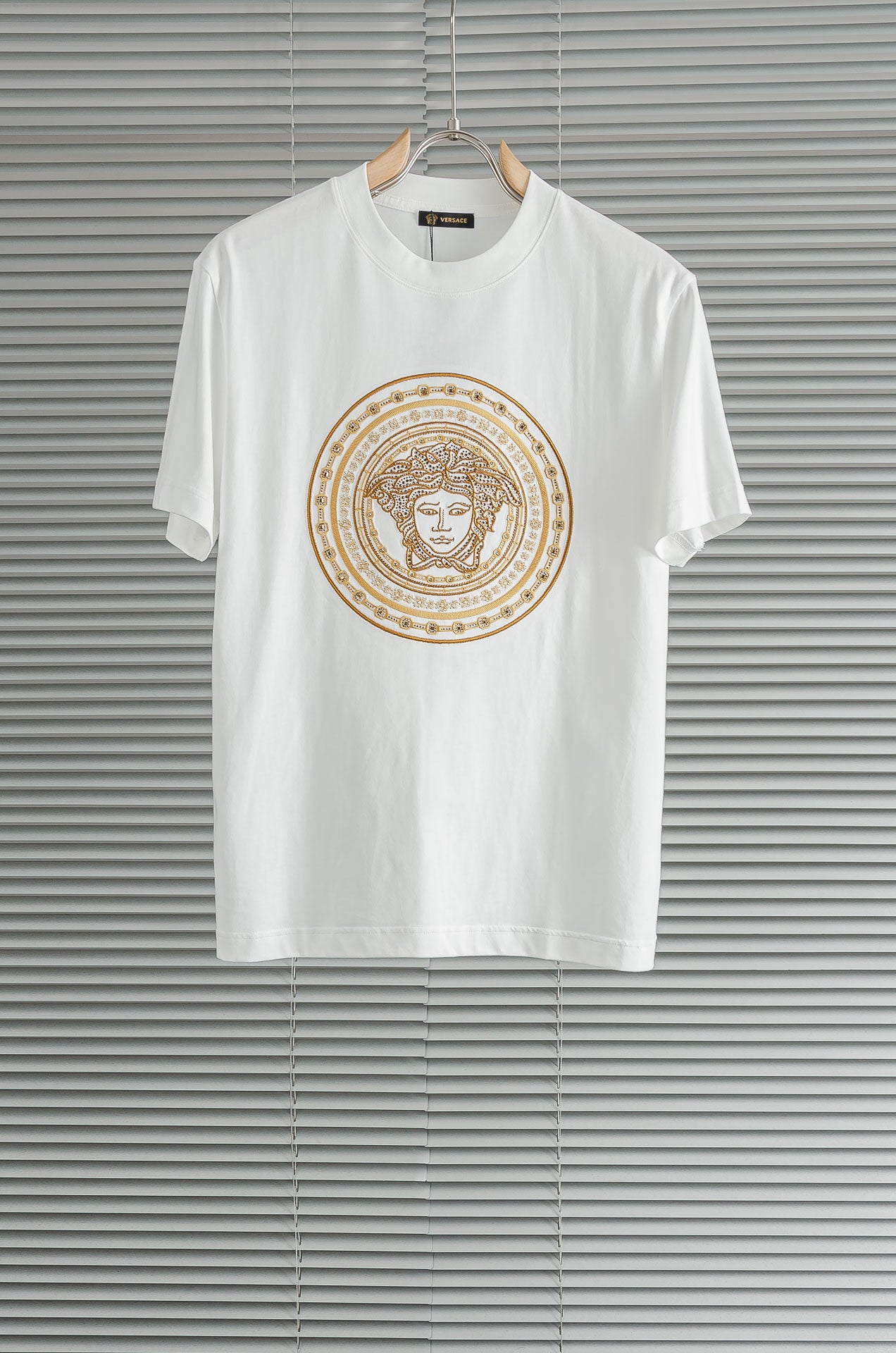 Versace white T-shirt with gold Medusa-style circular graphic on the chest