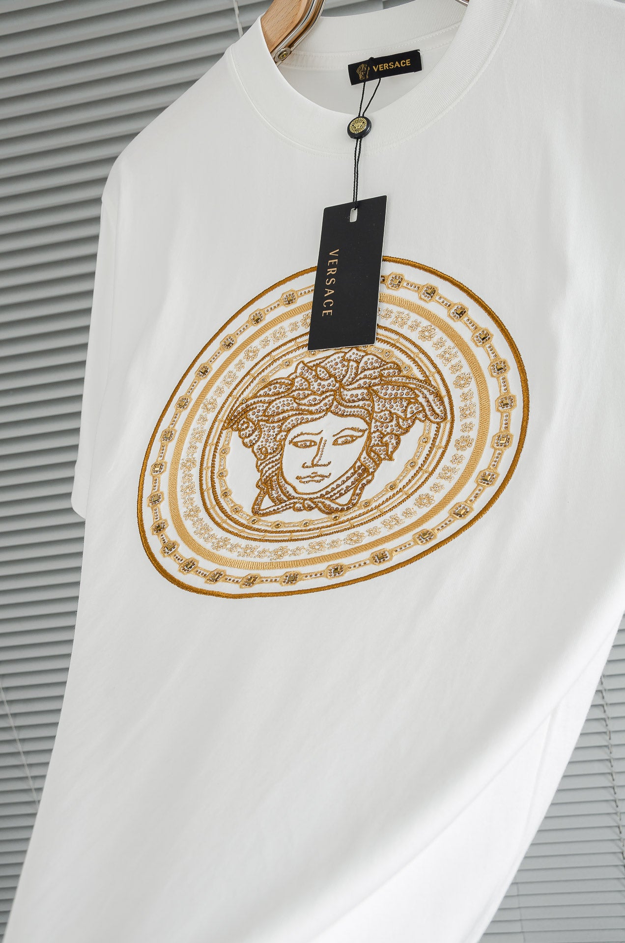 Versace white T-shirt with gold circular Medusa graphic; round neck with button placket