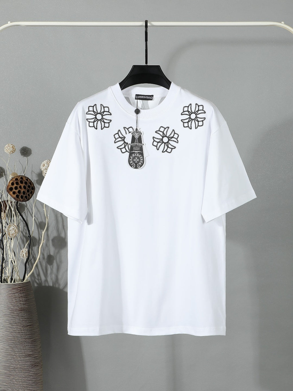 White short-sleeve T-shirt with black flower and charm graphic on the chest