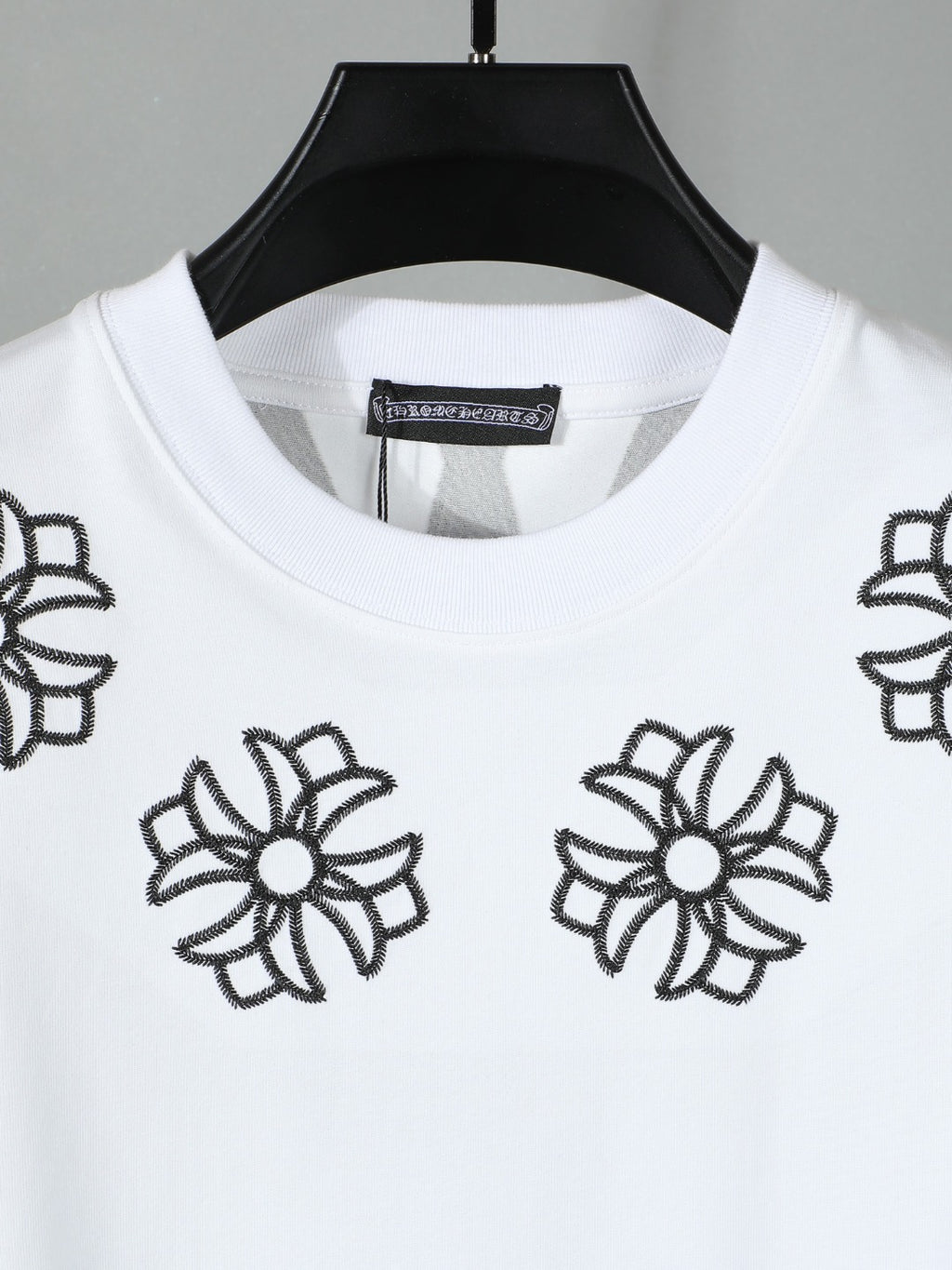 White short-sleeve T-shirt close-up of black flower embroidery around neckline