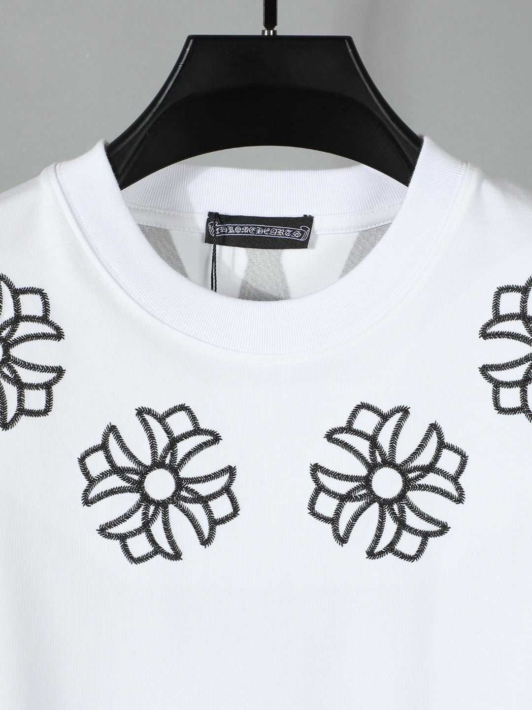 White short-sleeve T-shirt close-up of black flower embroidery around neckline