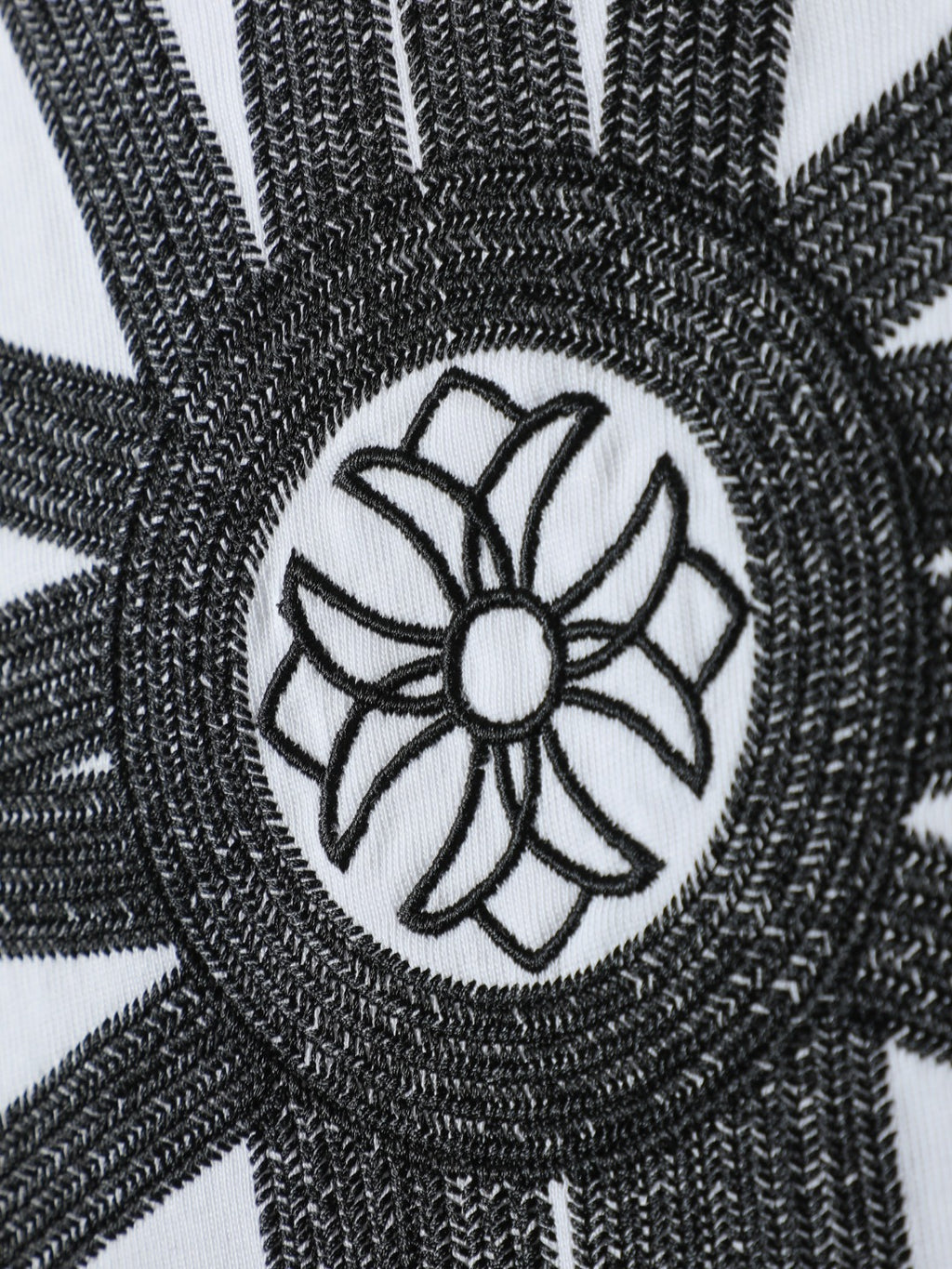 White T-shirt close-up of black embroidered circular flower emblem