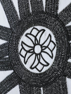 White T-shirt close-up of black embroidered circular flower emblem