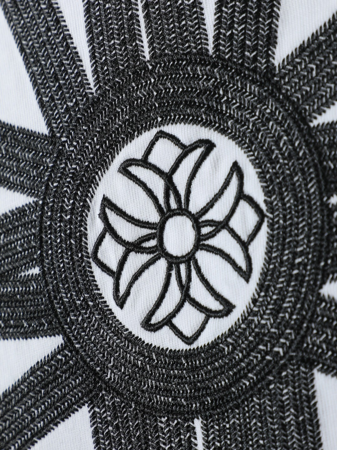White T-shirt close-up of black embroidered circular flower emblem