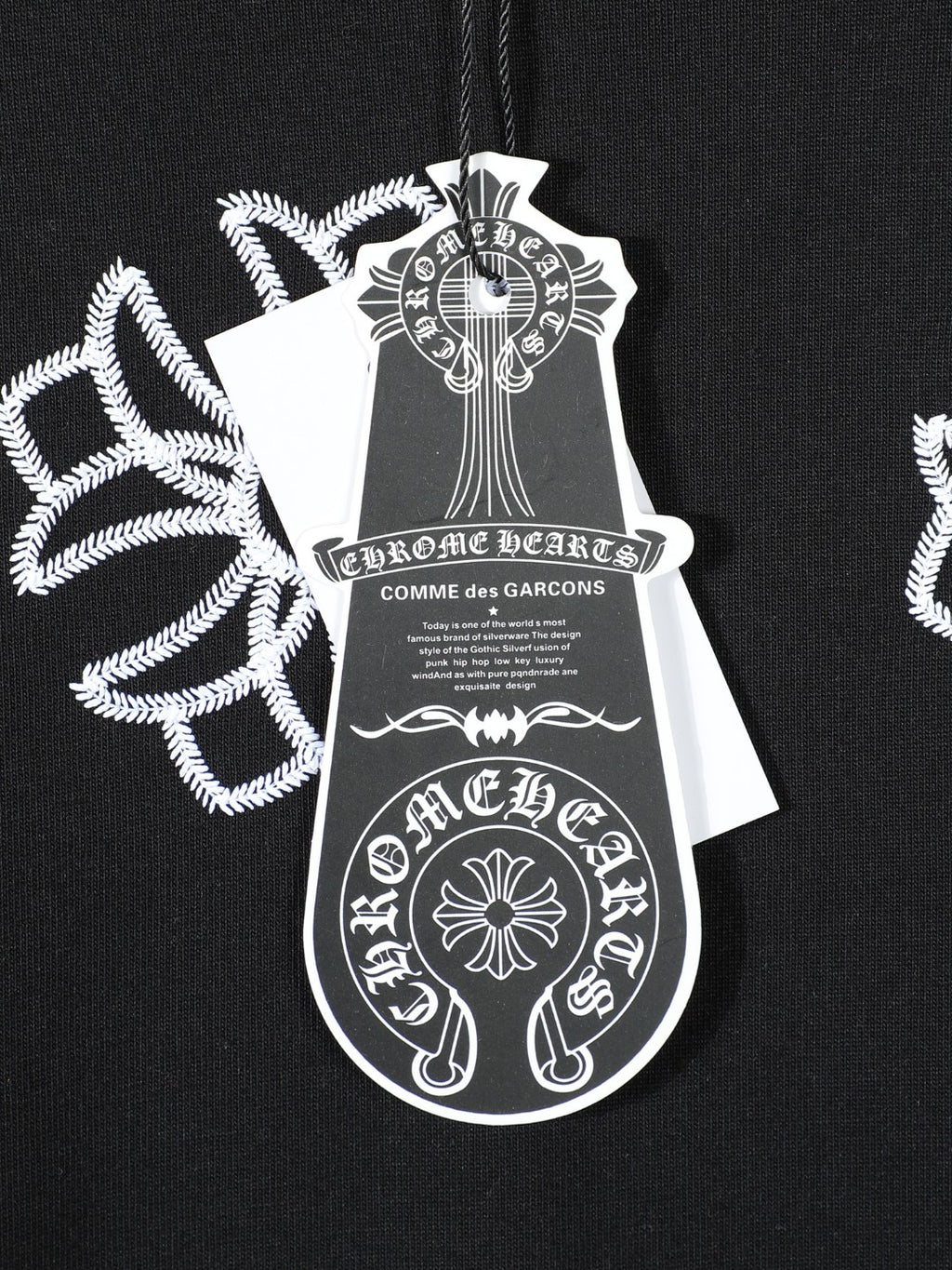 Black T-shirt chest tag artwork print with white cross-like floral motifs