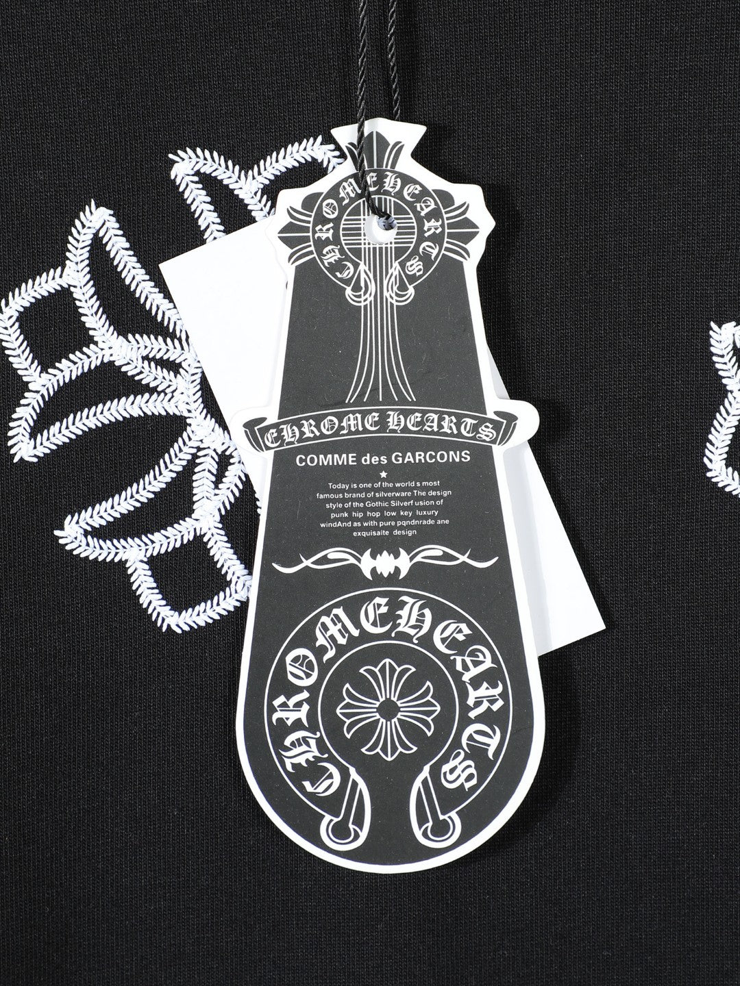 Black T-shirt chest tag artwork print with white cross-like floral motifs