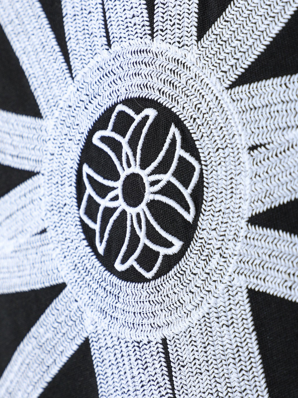 Close-up of black T-shirt with embroidered white flower motif and outlined center