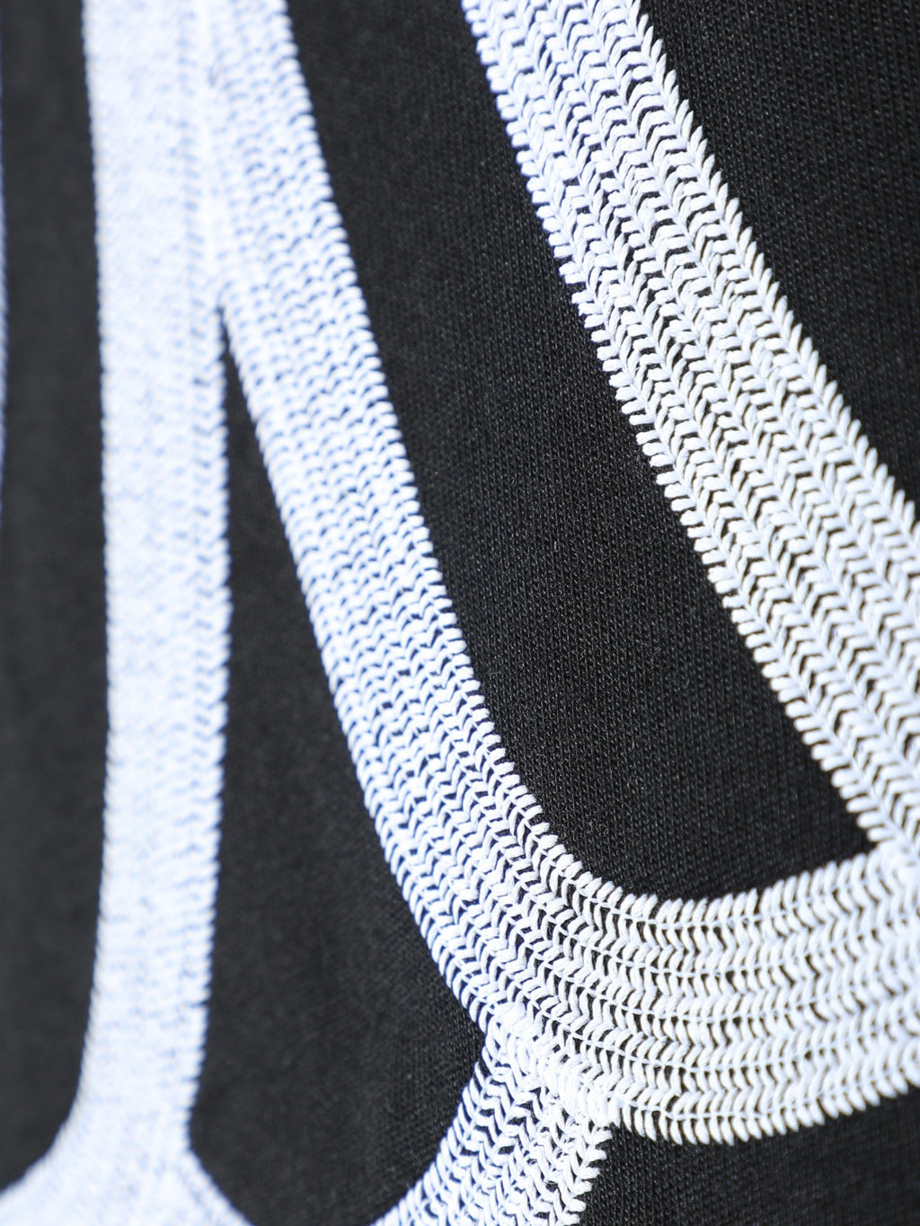 Close-up of black T-shirt fabric with white stitched curved line embroidery
