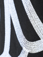 Close-up of black T-shirt fabric with white stitched curved line embroidery