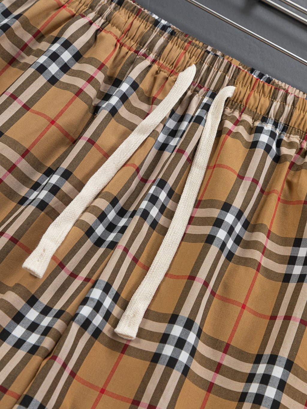 Plaid shorts fabric close-up with elastic waist and white drawstring