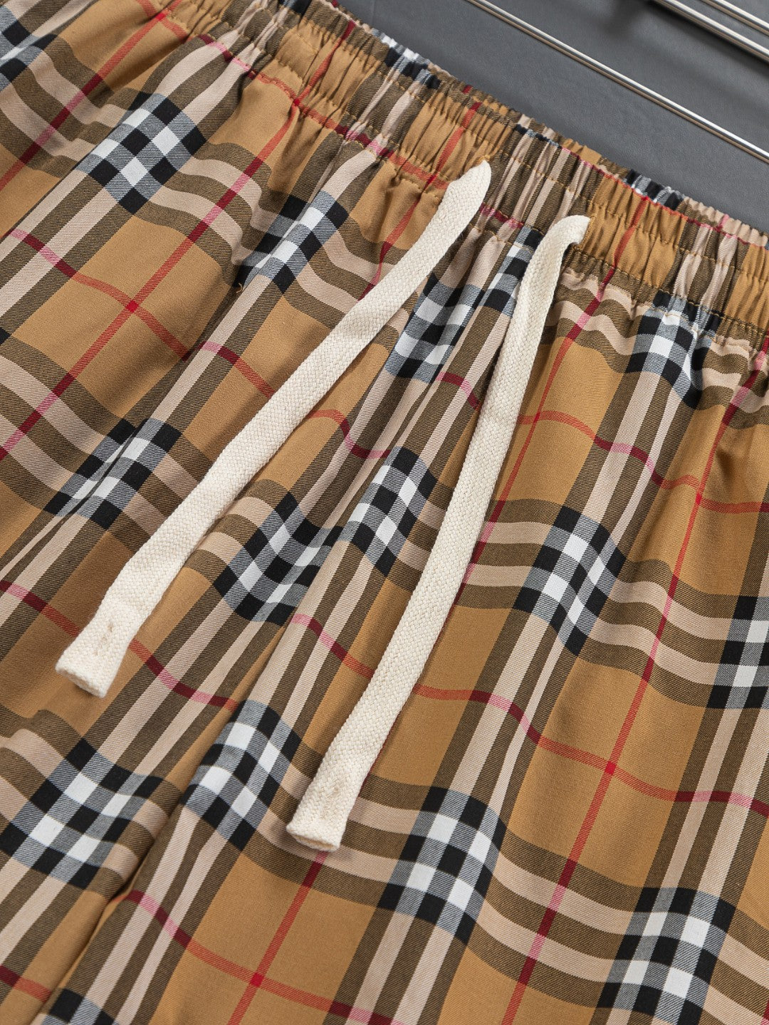 Plaid shorts fabric close-up with elastic waist and white drawstring
