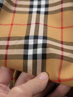 Plaid fabric close-up in tan, black, white, and red grid pattern