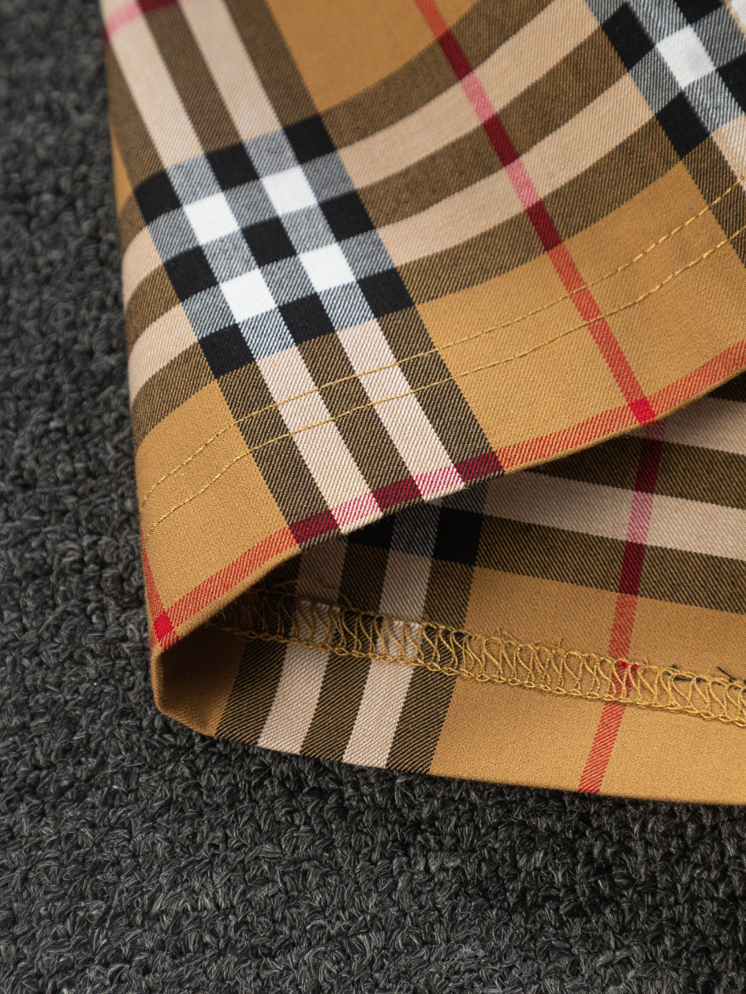 Plaid shorts hem with visible stitching and frayed edge detail