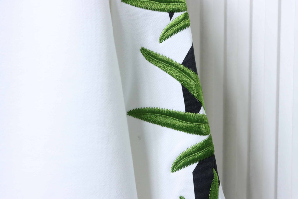 Off-white sweatshirt sleeve with embroidered green cannabis-leaf design