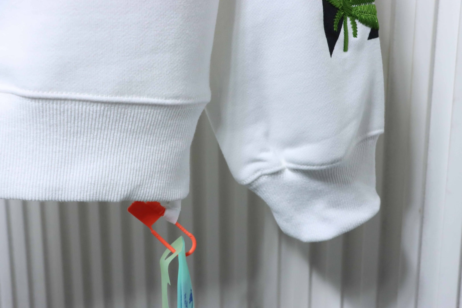 Off-white sweatshirt cuff and hem with hanging leaf graphic detail