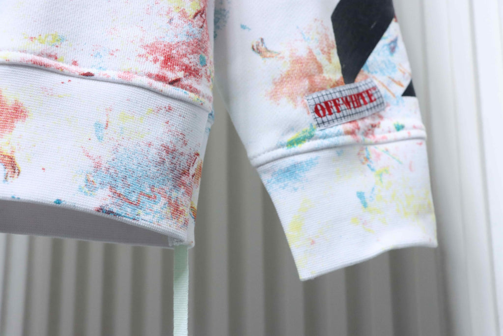 Off White hoodie sleeve hem with 'OFF' text patch and colorful paint splatter