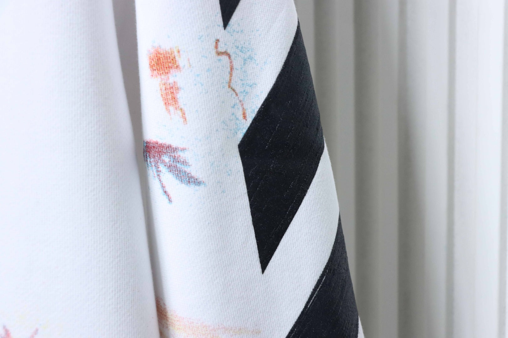 Off White hoodie sleeve with black graphic chevron over off-white paint print