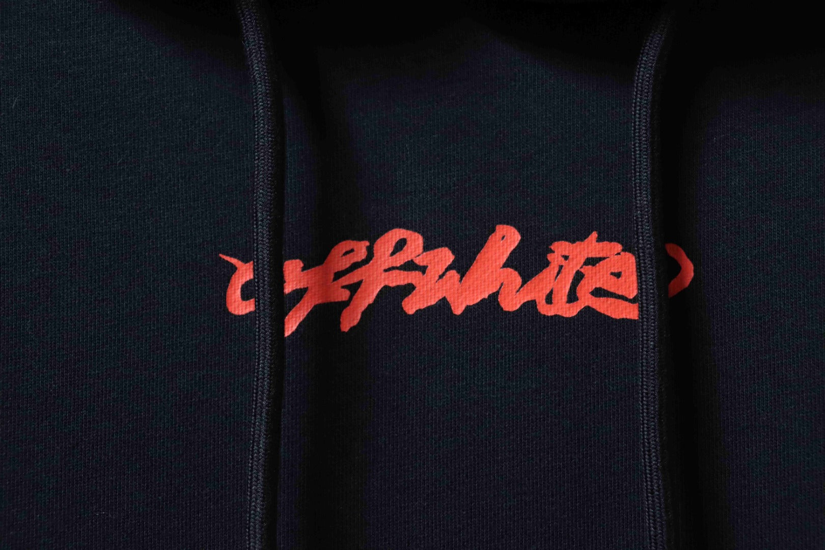 Off White hoodie close-up of red logo text on dark fabric