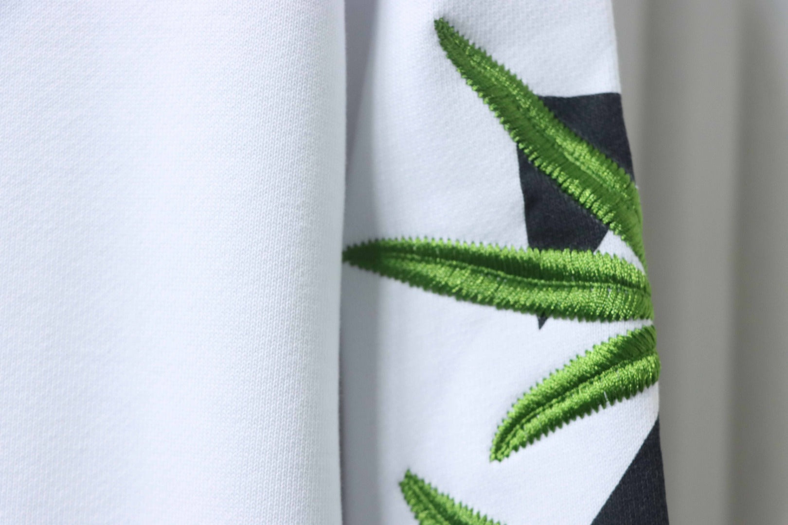 Off-White off-white hoodie sleeve detail with green leaf embroidery patch.
