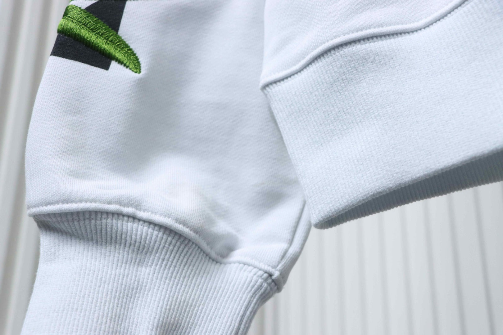 Off-White off-white hoodie pocket and sleeve hem detail with green leaf patch.