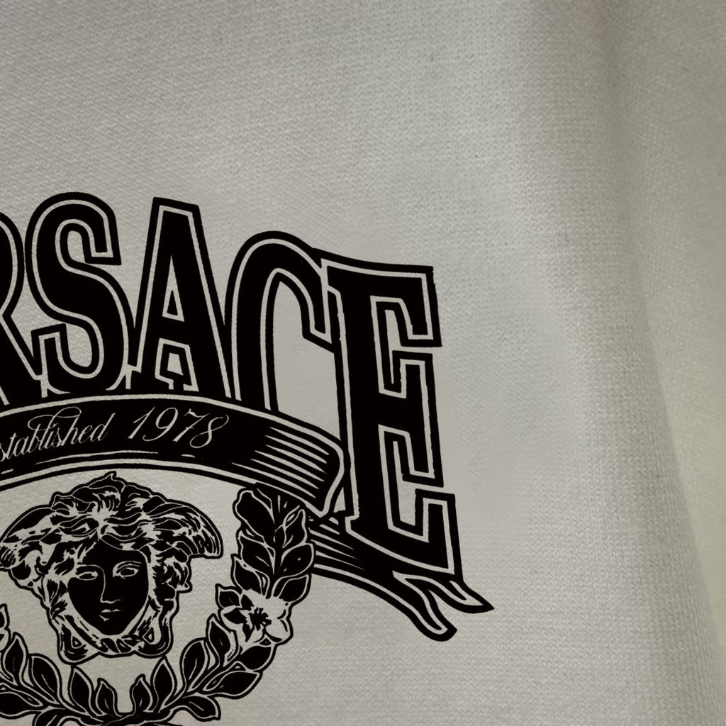 Off-white/cream long-sleeve T-shirt close-up of logo lettering and crest
