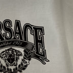 Off-white/cream long-sleeve T-shirt close-up of logo lettering and crest