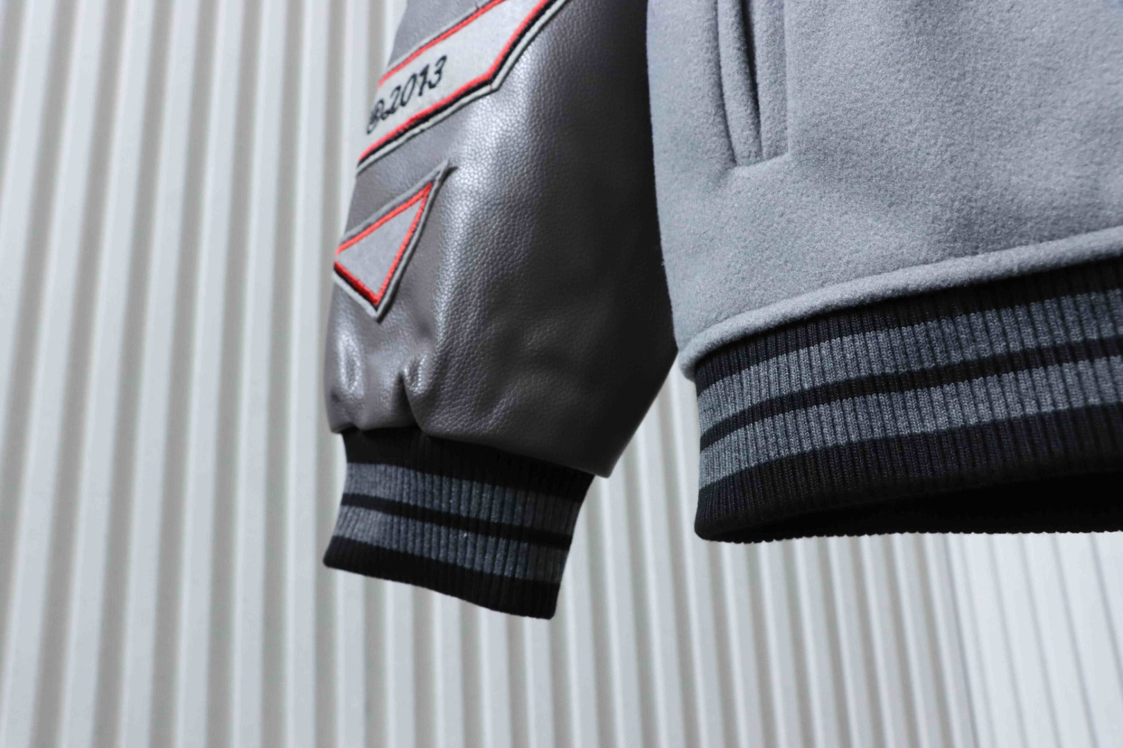 Off White grey jacket sleeve with black faux leather cuff and red logo patch