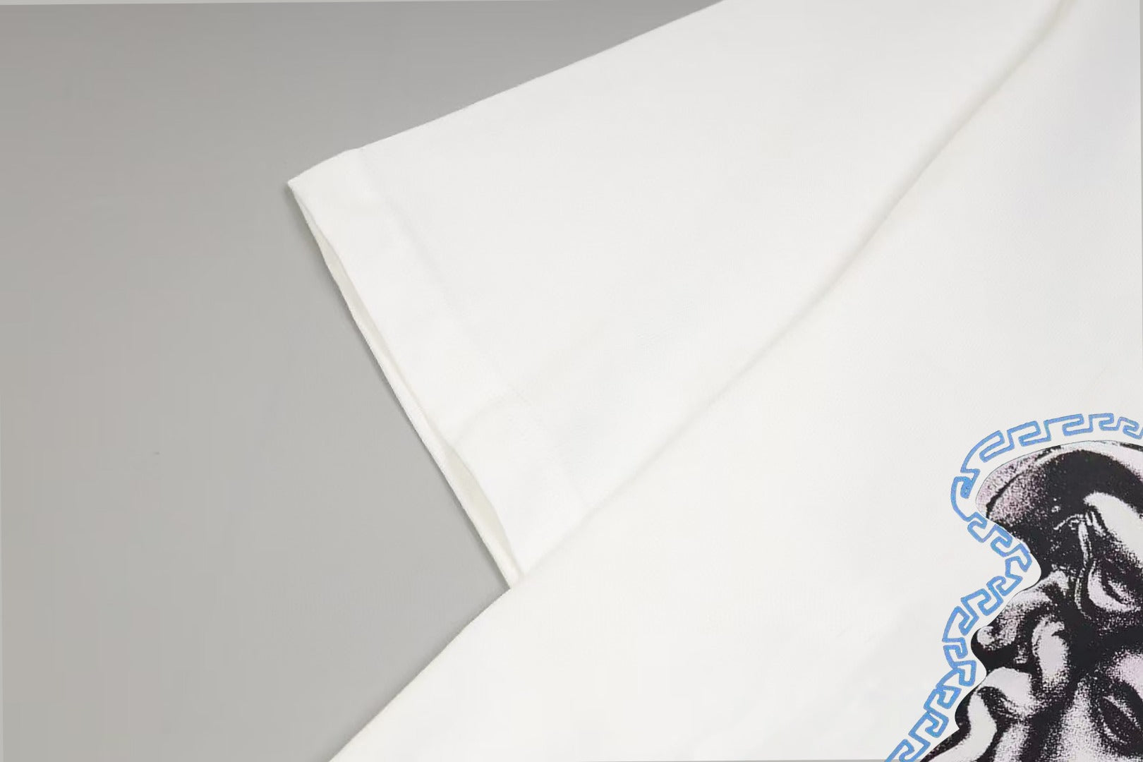 White Versace T-shirt sleeve and shoulder seam with partial Medusa print