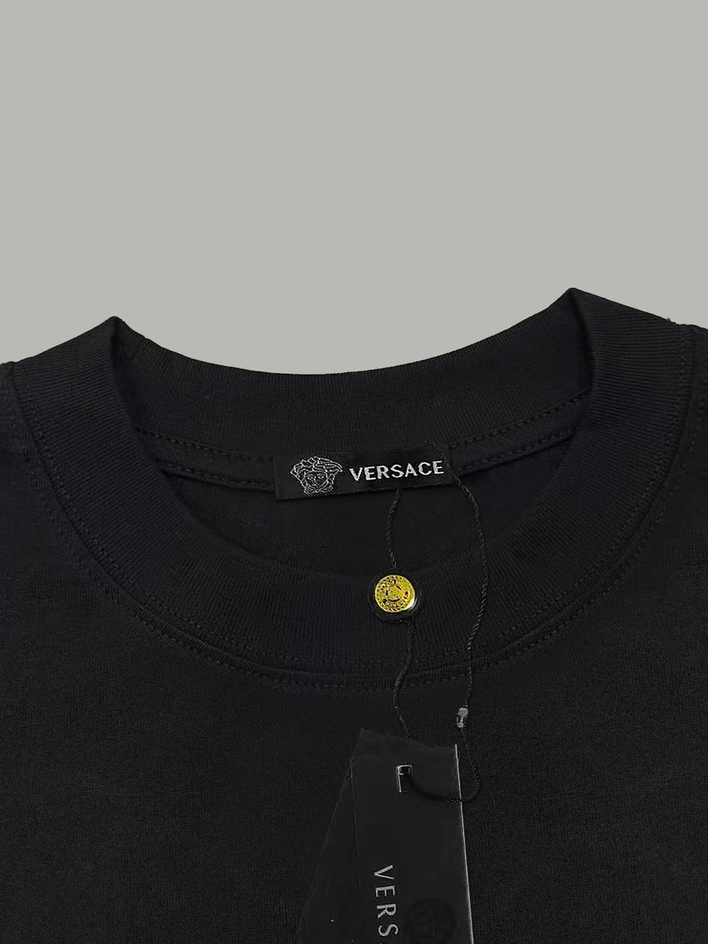 Black T-shirt neckline with Versace neck label and small hanging tag