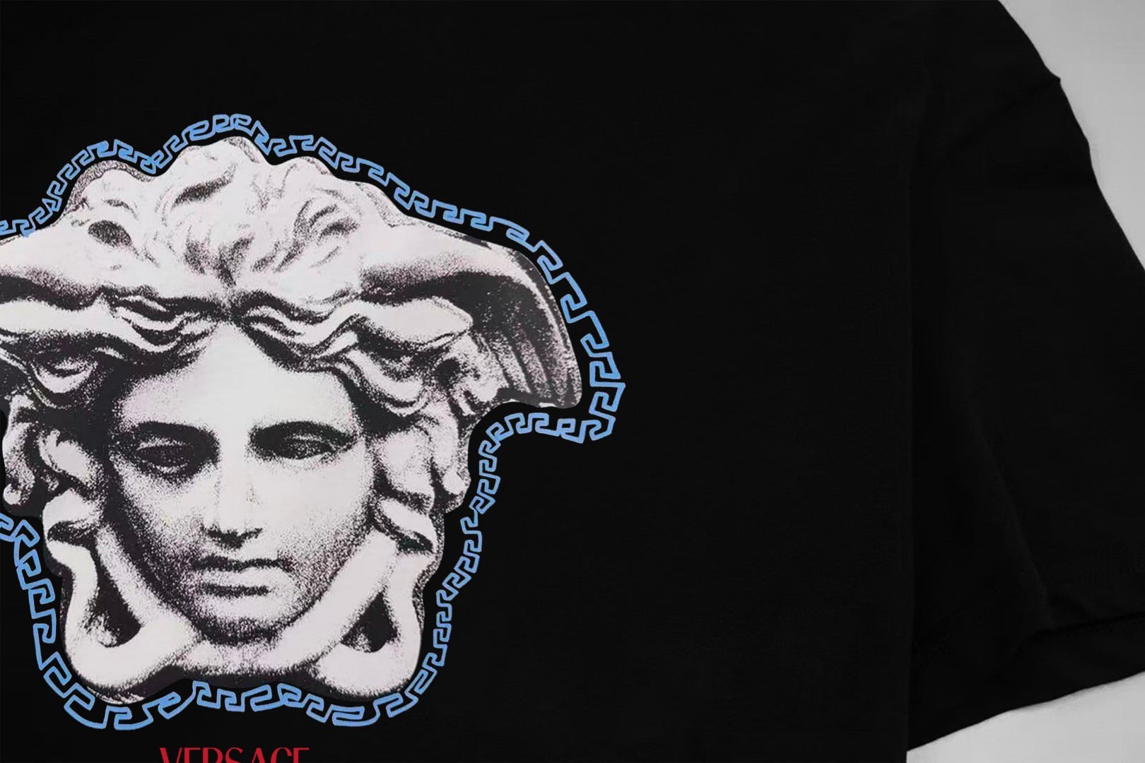 Black T-shirt chest graphic of Medusa in white with blue Greek key border