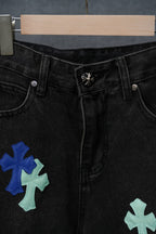 Black denim pants waist close-up with button closure and cross patches